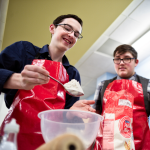 Two male participant baking at cake